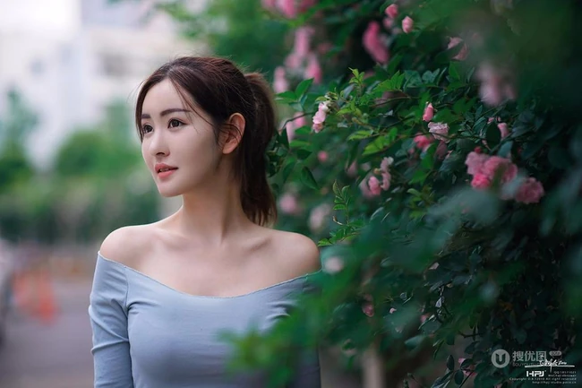 气质美丽女孩蔷薇花前驻足流连，着V领上衣搭牛仔裙艺术摄影图片