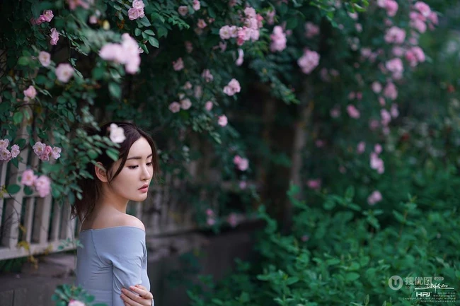 气质美丽女孩蔷薇花前驻足流连，着V领上衣搭牛仔裙艺术摄影图片