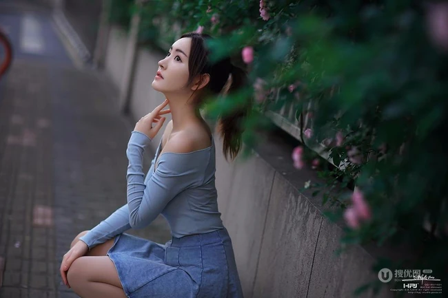 气质美丽女孩蔷薇花前驻足流连，着V领上衣搭牛仔裙艺术摄影图片