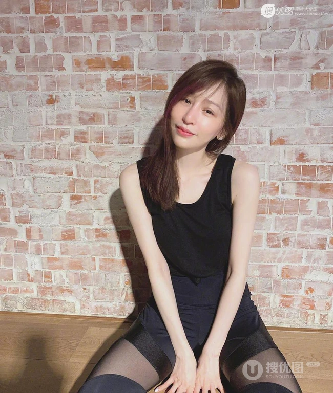 王心凌黑色背心搭配轻纱袜装拼接长裤蹲坐气质图片