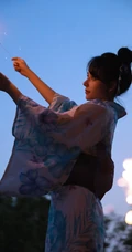 夜幕快降临时手拿燃烧烟花棒的和服装漂亮清新女生唯美写真