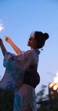 夜幕快降临时手拿燃烧烟花棒的和服装漂亮清新女生唯美写真