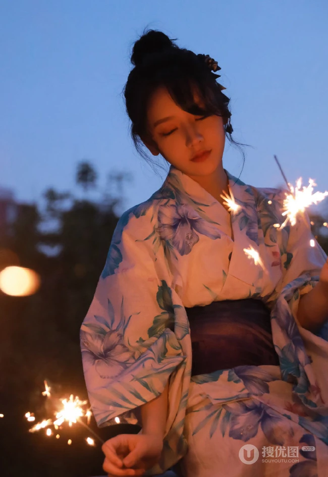 夜幕快降临时手拿燃烧烟花棒的和服装漂亮清新女生唯美写真