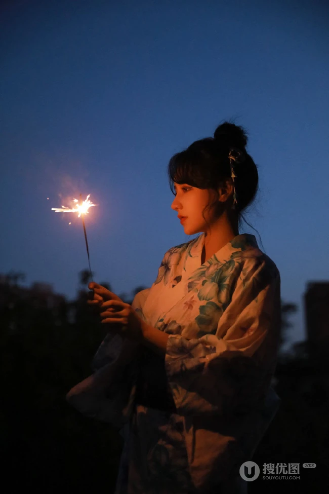 夜幕快降临时手拿燃烧烟花棒的和服装漂亮清新女生唯美写真