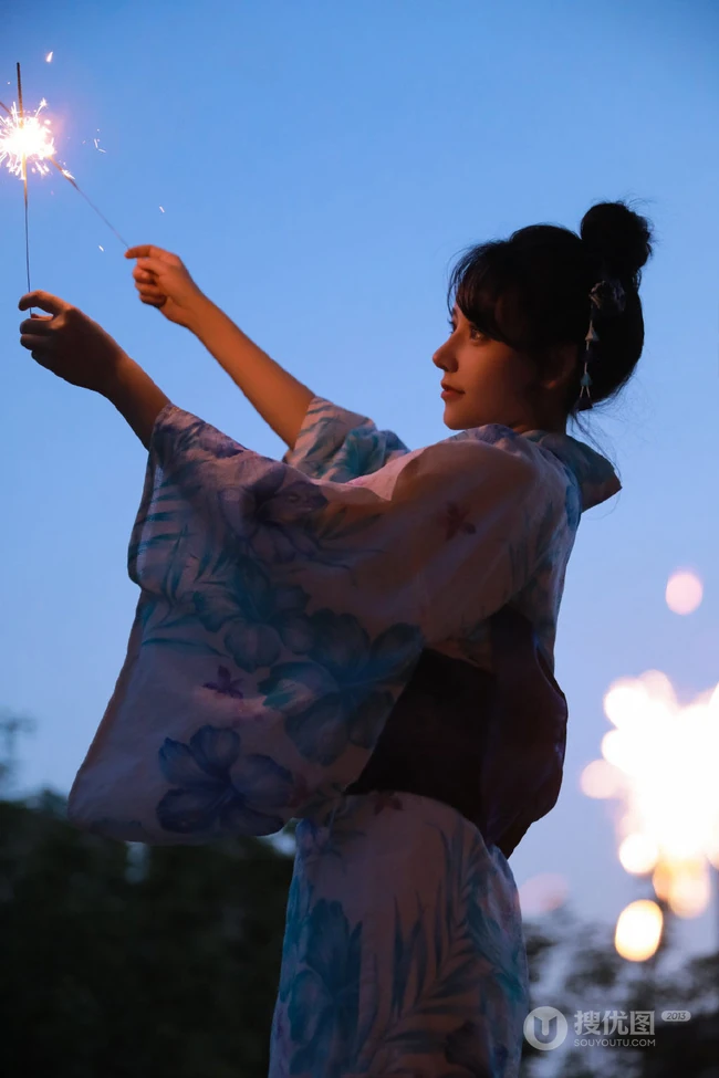 夜幕快降临时手拿燃烧烟花棒的和服装漂亮清新女生唯美写真