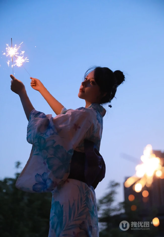 夜幕快降临时手拿燃烧烟花棒的和服装漂亮清新女生唯美写真