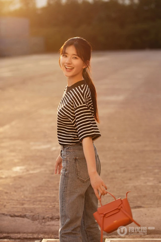 赵露思身穿斑马纹T恤和牛仔裤，手拿包包户外露甜美笑容写真