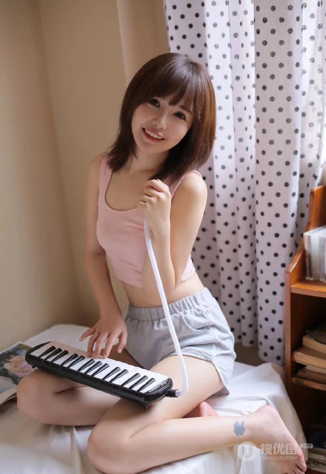 玩电子琴的粉衣短裤可爱少女浅笑动人居家悠闲室内写真图片