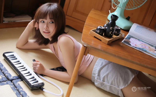 玩电子琴的粉衣短裤可爱少女浅笑动人居家悠闲室内写真图片