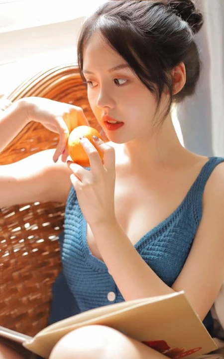 气质清纯低领装短裤少女居家看杂志，吃水果悠闲曝光写真图片