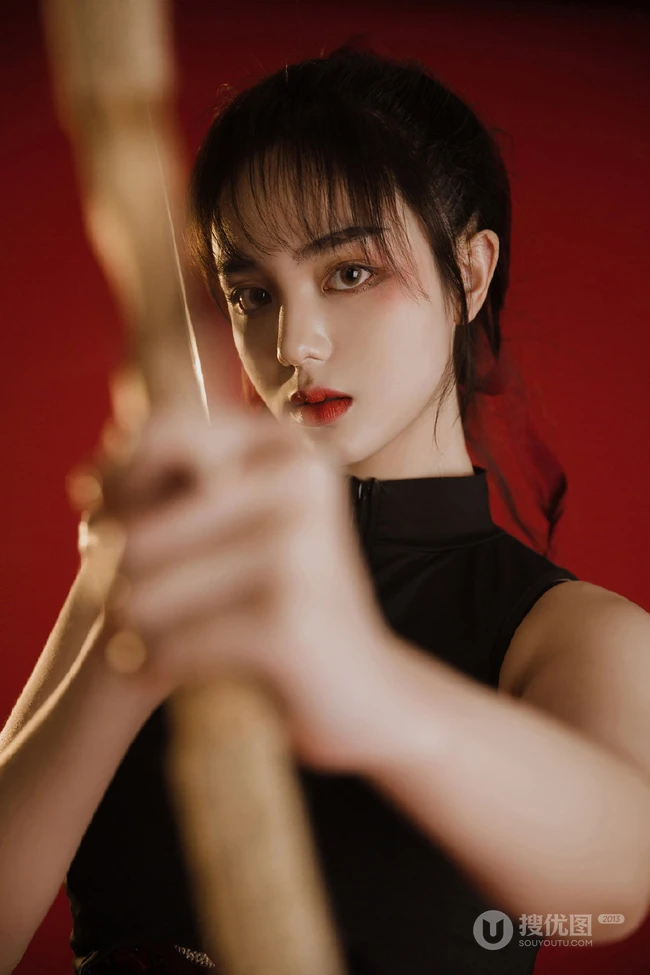 背弓箭的少女，红色背景前的背箭长发少女飒美摄影艺术写真照