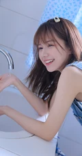 美丽可爱的苗条女孩，穿着背带牛仔裤洗衣房蹲着玩水龙头俏皮写真美照