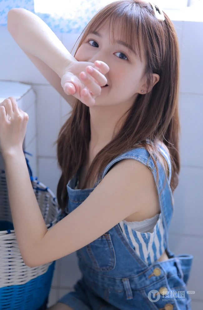 美丽可爱的苗条女孩，穿着背带牛仔裤洗衣房蹲着玩水龙头俏皮写真美照