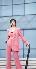 万茜身着粉色西服礼裙衣酷飒写真，大厦前的绿色草地上休庭信步