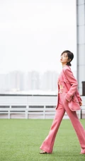 万茜身着粉色西服礼裙衣酷飒写真，大厦前的绿色草地上休庭信步
