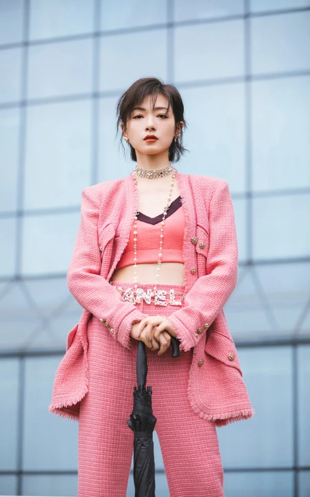万茜身着粉色西服礼裙衣酷飒写真，大厦前的绿色草地上休庭信步