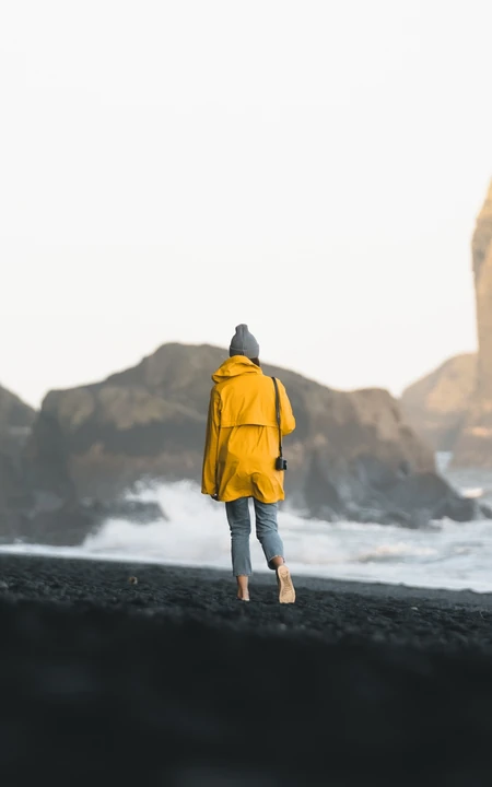 大浪拍打着礁石，海滩上散步的欧美美女背景手机壁纸