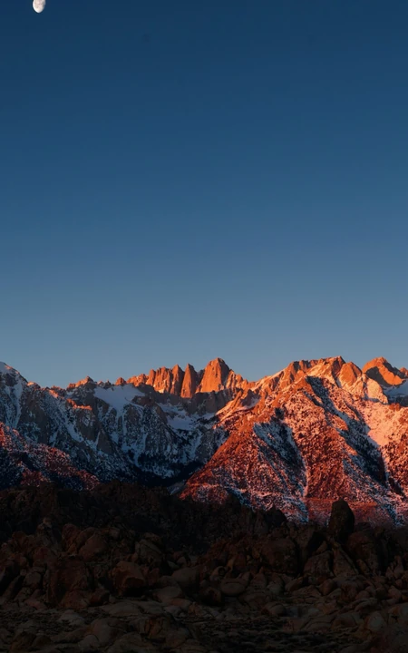 夕阳照射着高山，月亮已经升起的自然风景手机壁纸