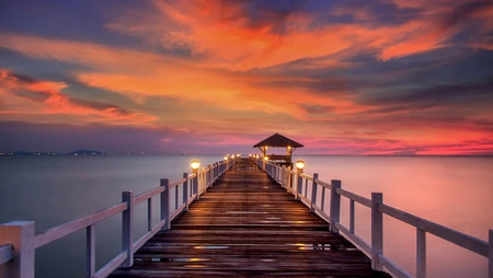 橙红彩霞海岸线，海上的礁石木栈道的唯美风景壁纸
