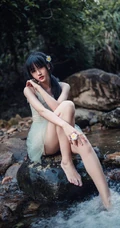 清澈见底的山间溪流中，一个穿着蓝色连衣裙的美丽麻花辫女孩摄影艺术照