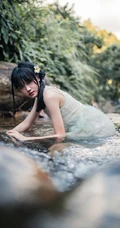 清澈见底的山间溪流中，一个穿着蓝色连衣裙的美丽麻花辫女孩摄影艺术照
