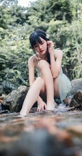 清澈见底的山间溪流中，一个穿着蓝色连衣裙的美丽麻花辫女孩摄影艺术照