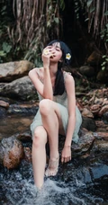 清澈见底的山间溪流中，一个穿着蓝色连衣裙的美丽麻花辫女孩摄影艺术照