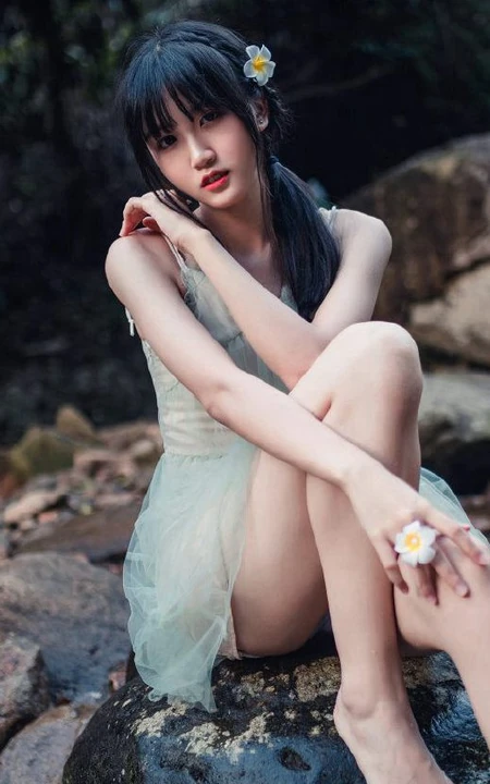 清澈见底的山间溪流中，一个穿着蓝色连衣裙的美丽麻花辫女孩摄影艺术照