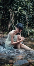 清澈见底的山间溪流中，一个穿着蓝色连衣裙的美丽麻花辫女孩摄影艺术照