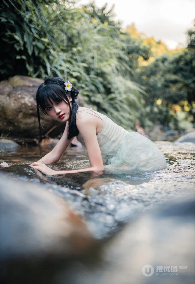 清澈见底的山间溪流中，一个穿着蓝色连衣裙的美丽麻花辫女孩摄影艺术照