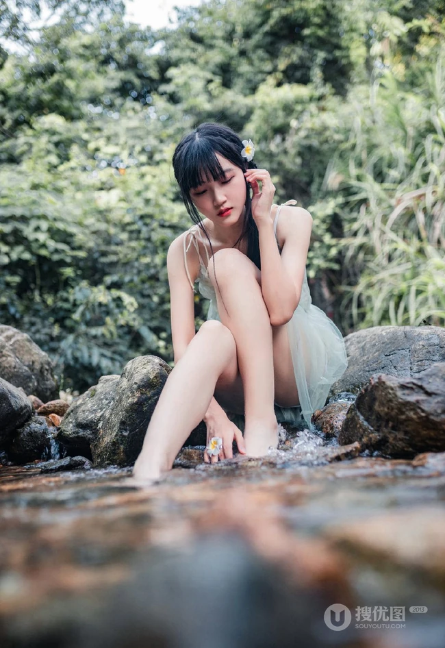 清澈见底的山间溪流中，一个穿着蓝色连衣裙的美丽麻花辫女孩摄影艺术照