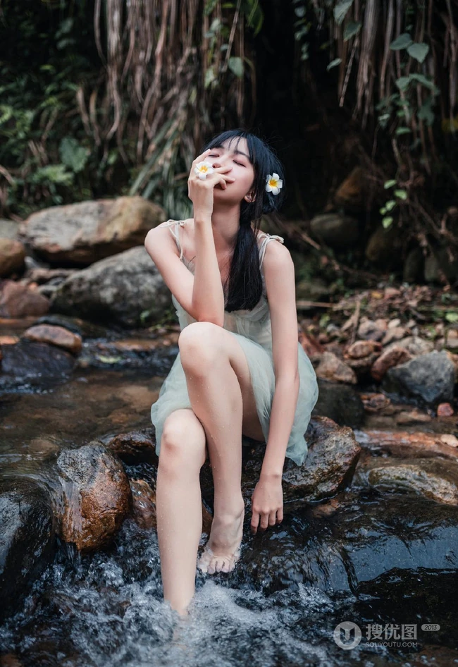 清澈见底的山间溪流中，一个穿着蓝色连衣裙的美丽麻花辫女孩摄影艺术照