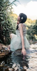 清澈见底的山间溪流中，一个穿着蓝色连衣裙的美丽麻花辫女孩摄影艺术照