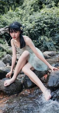 清澈见底的山间溪流中，一个穿着蓝色连衣裙的美丽麻花辫女孩摄影艺术照