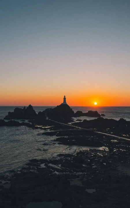 礁石海岸灯塔升起的太阳风景