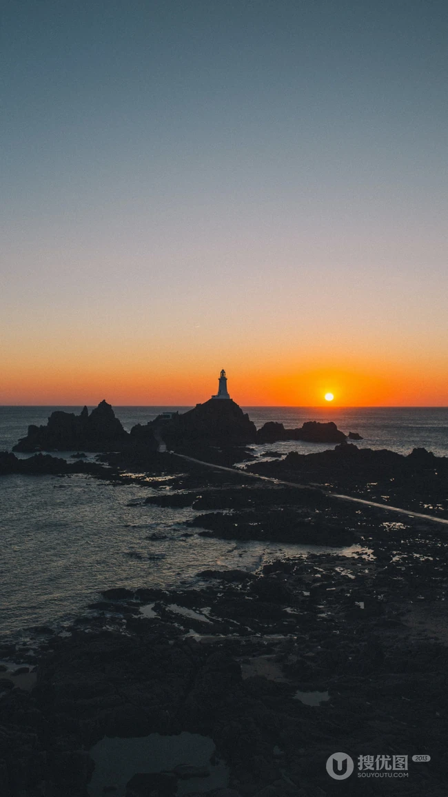 礁石海岸灯塔升起的太阳风景