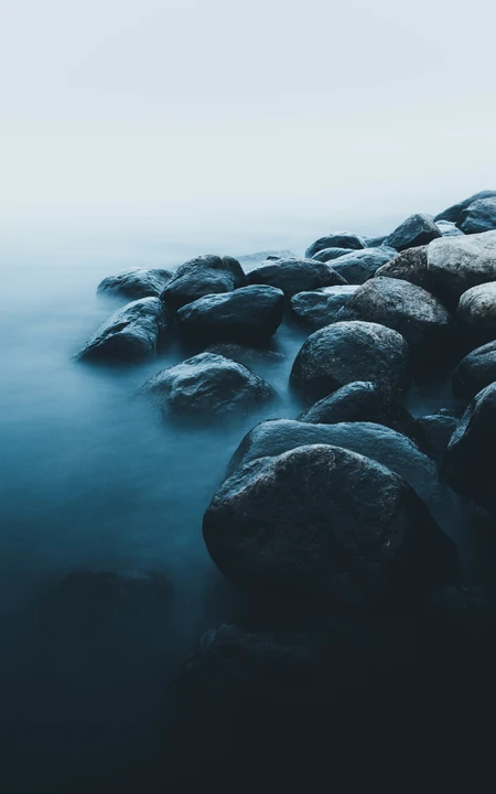 雾气重重的海边，海边的礁石摄影高清手机壁纸