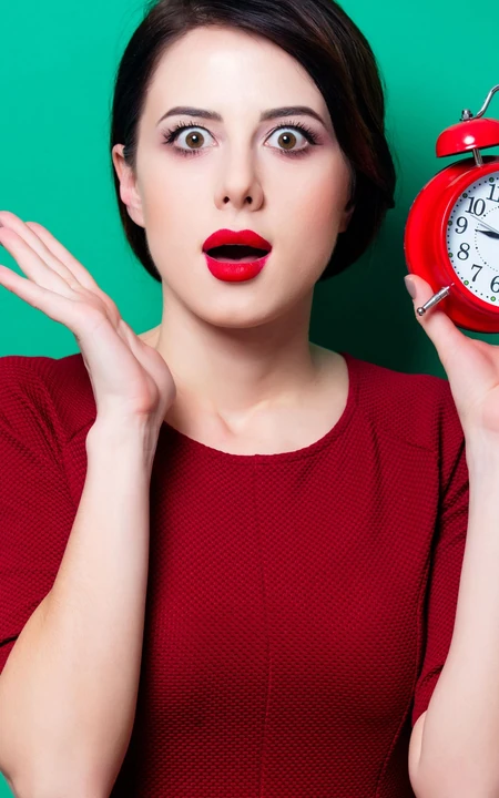 手拿小闹钟 身着红色连衣裙 红唇 大眼 精致美妆的外国女人手机壁纸图片
