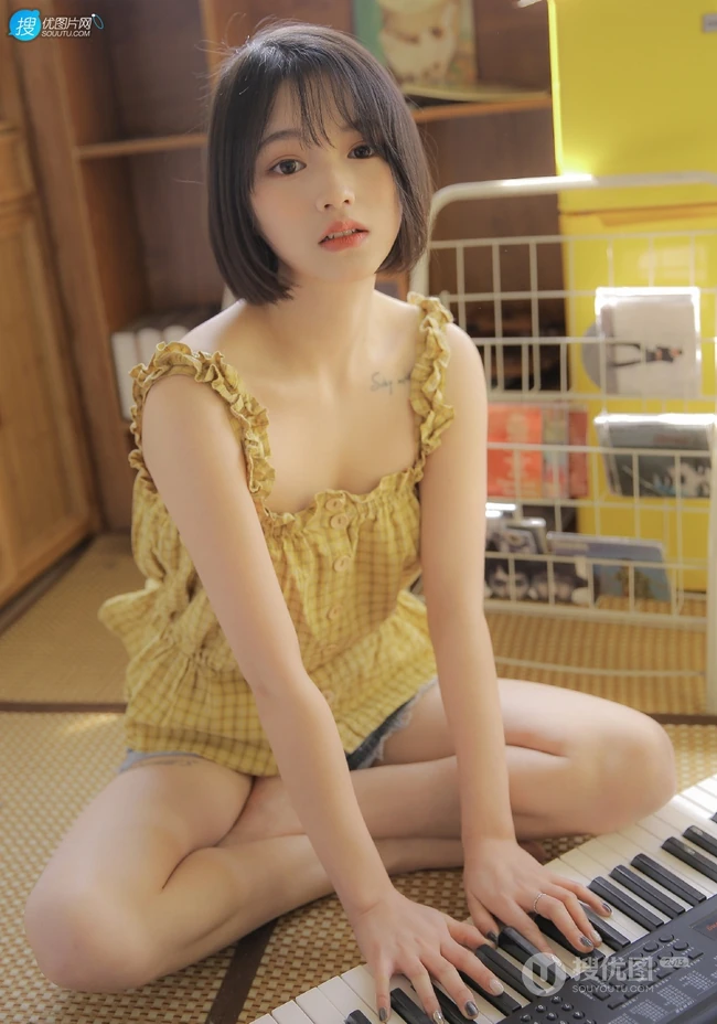 齐下巴短发娇小玲珑纹身少女黄色肩带衣牛仔短裤居家温暖室内照片