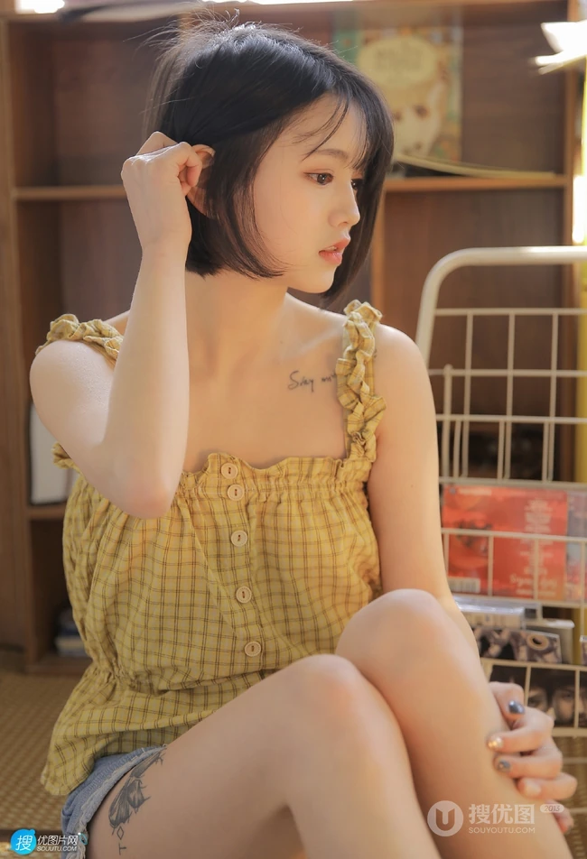 齐下巴短发娇小玲珑纹身少女黄色肩带衣牛仔短裤居家温暖室内照片