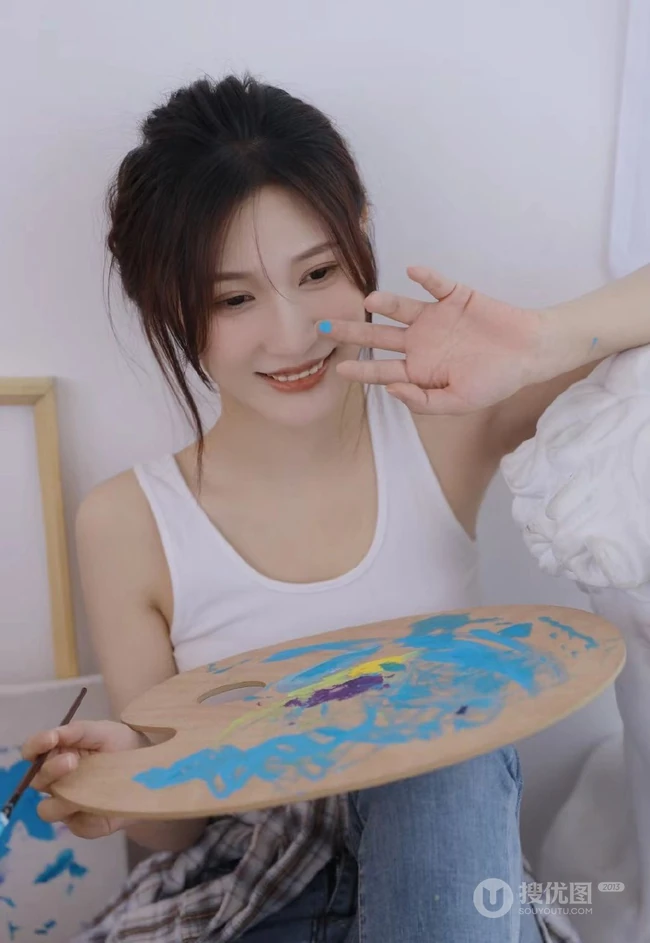 认真画画的样子好美，画室里穿着白色肩带文胸衣牛仔裤的女生写真图片
