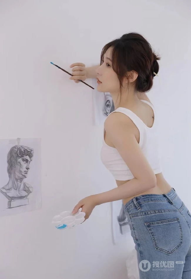 认真画画的样子好美，画室里穿着白色肩带文胸衣牛仔裤的女生写真图片