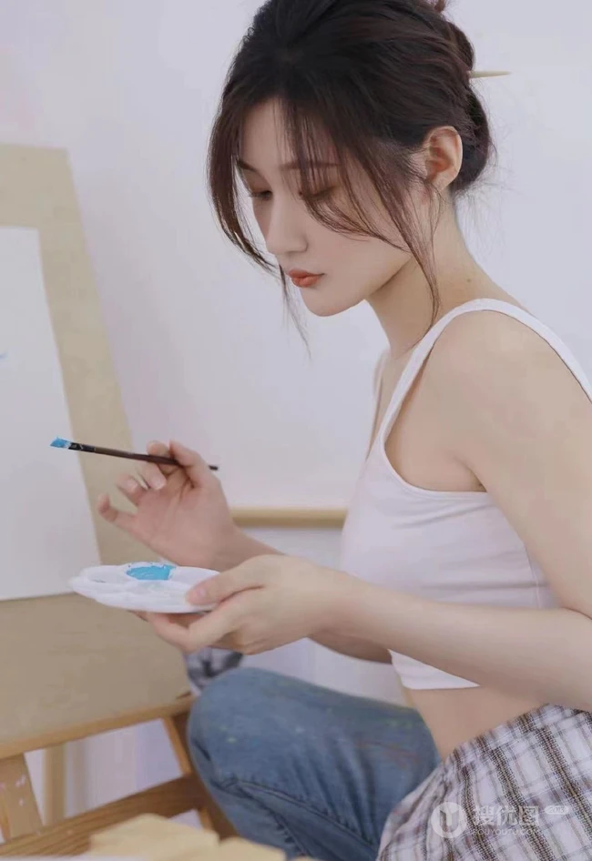 认真画画的样子好美，画室里穿着白色肩带文胸衣牛仔裤的女生写真图片