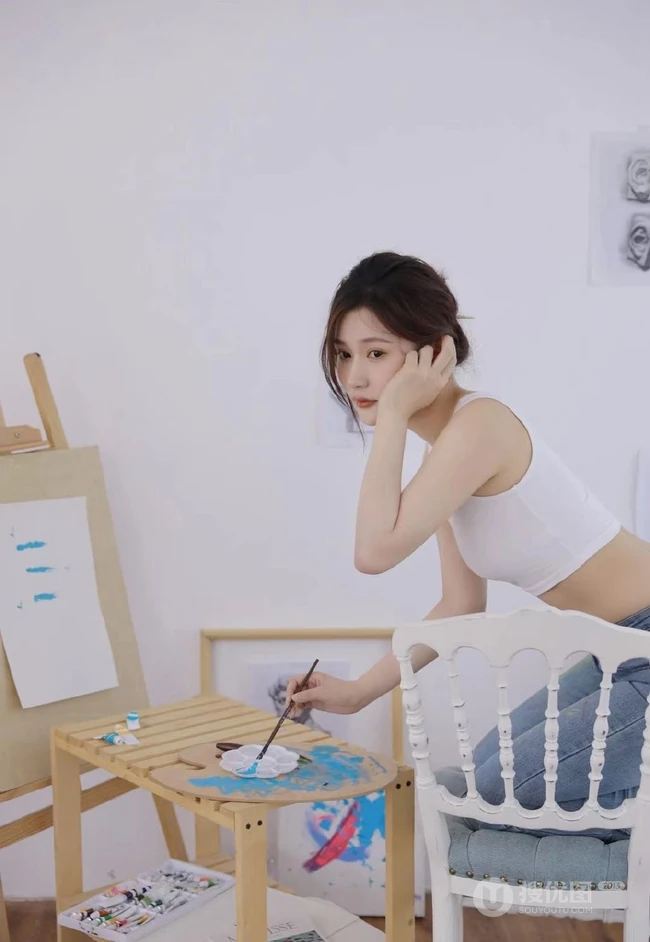 认真画画的样子好美，画室里穿着白色肩带文胸衣牛仔裤的女生写真图片