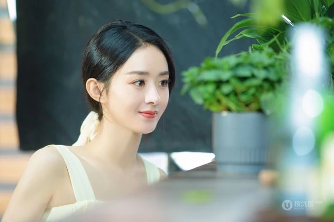 赵丽颖秀发披肩伺弄花草写真，身着肩带黄裙尽显温柔气质魅力
