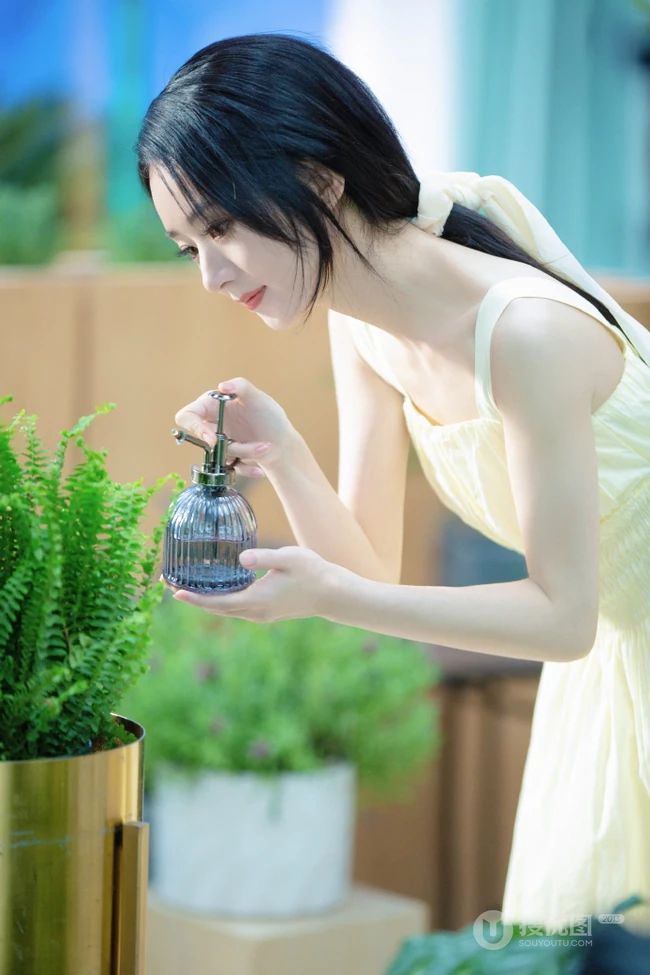 赵丽颖秀发披肩伺弄花草写真，身着肩带黄裙尽显温柔气质魅力