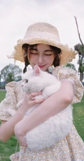 许佳琪头戴草帽，手抱猫咪，身穿小碎花裙户外清新写真图片