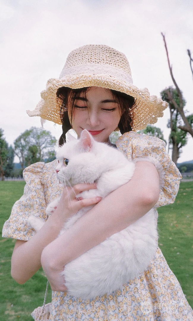 许佳琪头戴草帽，手抱猫咪，身穿小碎花裙户外清新写真图片