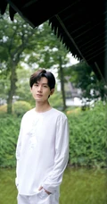 成毅一身白衣在绿意盎然的庭院中闲庭信步帅气写真照片