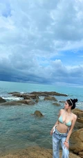 浪漫海边礁石上，身着蓝色肩带泳装加牛仔裤的优雅身形女生写真照片